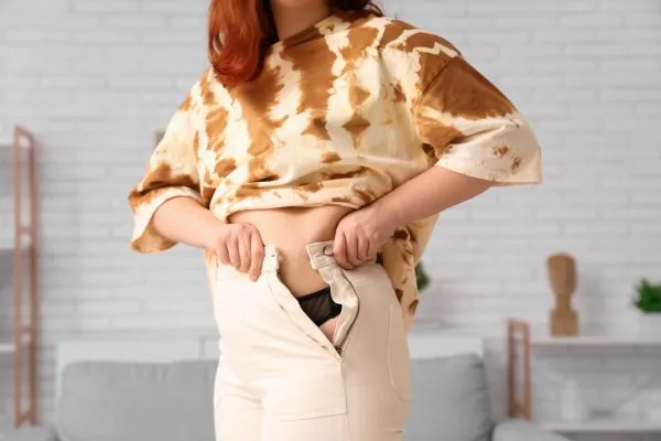 Image of woman trying to do her trousers up after pregnancy weight gain Smethwick